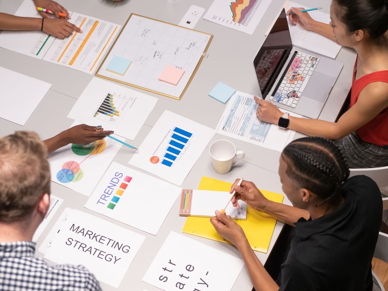 Vue aérienne d’une équipe variée examinant des stratégies marketing à l’aide de graphiques et de diagrammes.